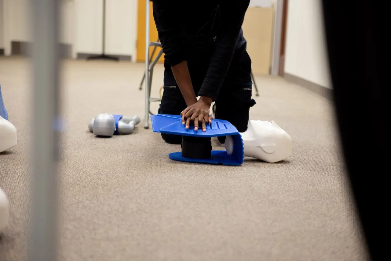 Learner performing chest compressions on a CPR mannequin